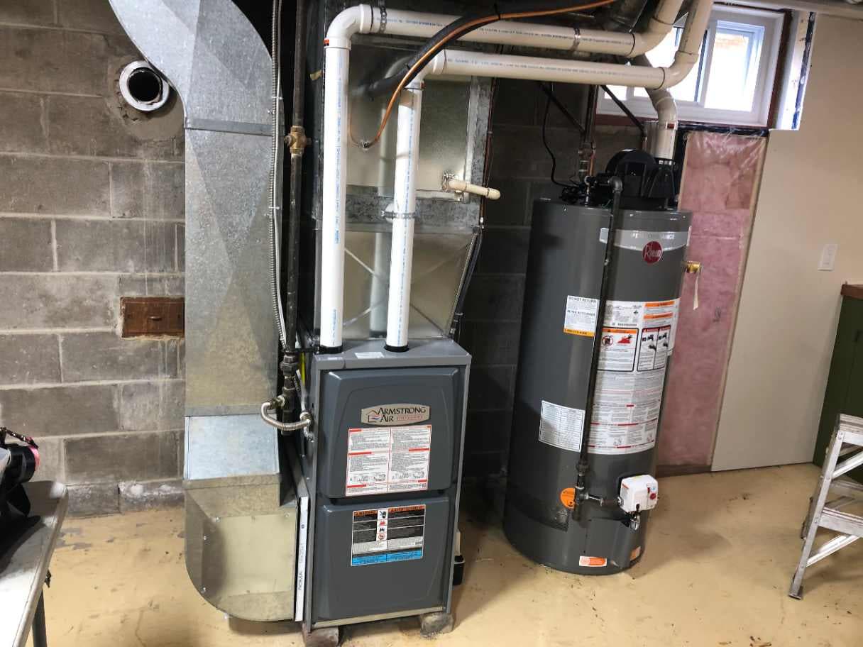 Hot water storage tank next to a furnace in a mechanical room